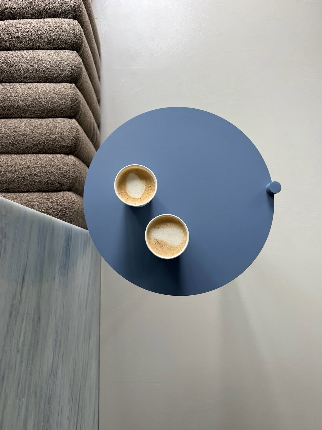 Two coffees on a small blue table inside Some Good Moves.